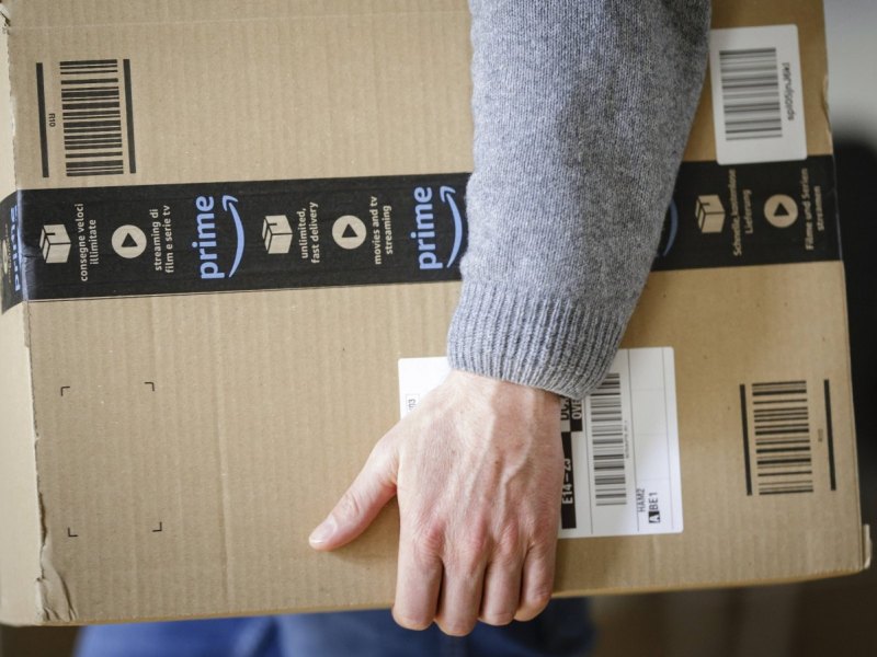 Mann mit Amazon Prime Paket in der Hand.