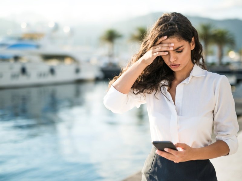 Frau guckt gestresst auf ihr Handy.