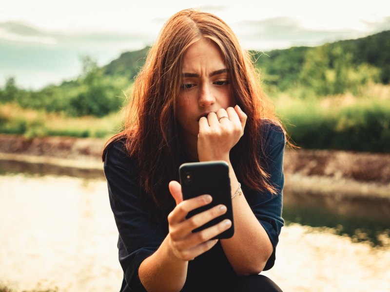 Frau schaut besorgt auf ihr Handy.