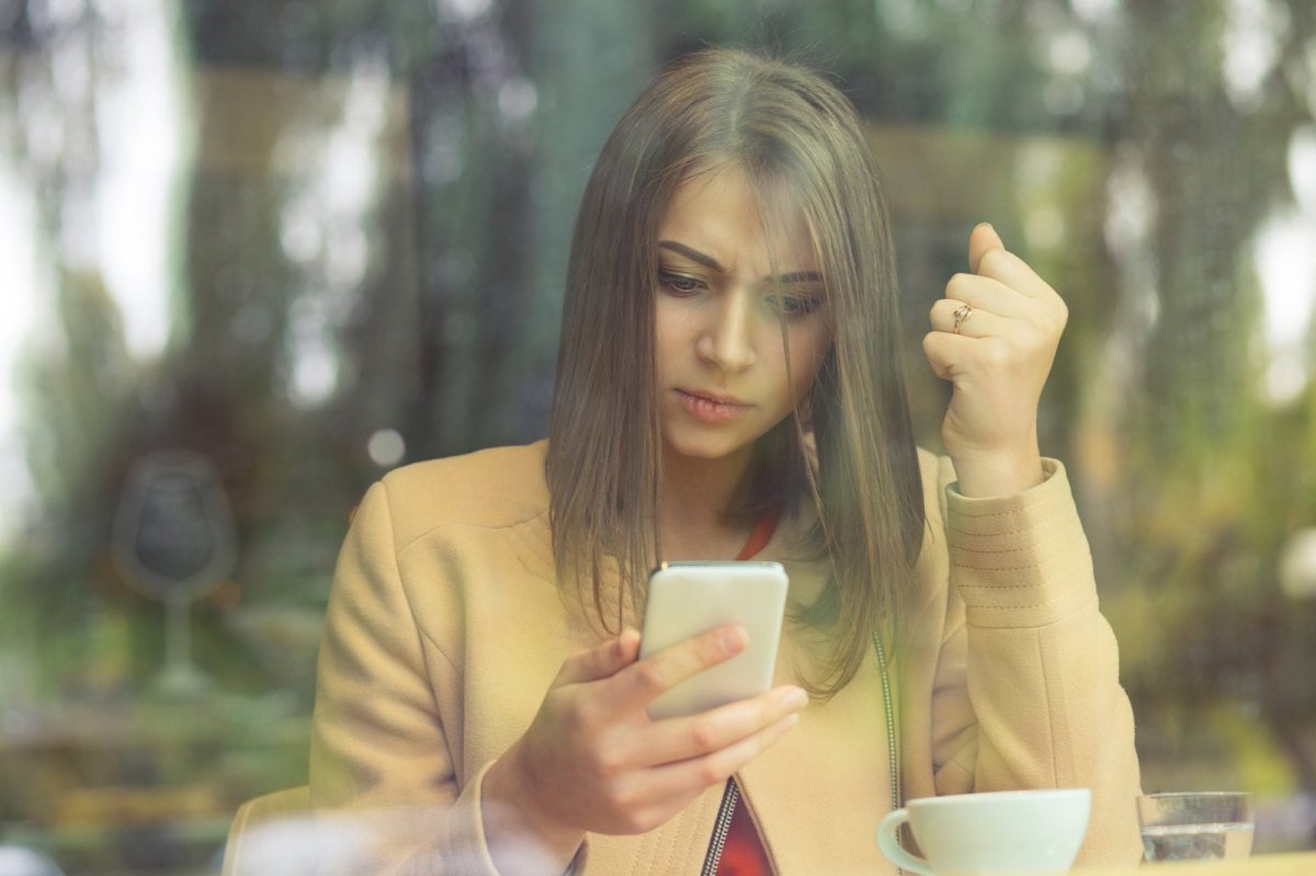 Frau schaut irritiert auf ihr Handy.