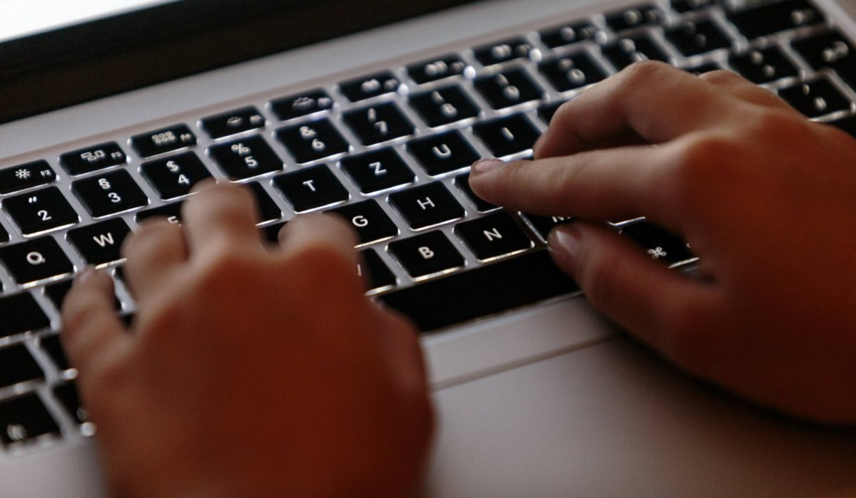 Hände tippen auf einer Tastatur eines MacBook Pros herum.