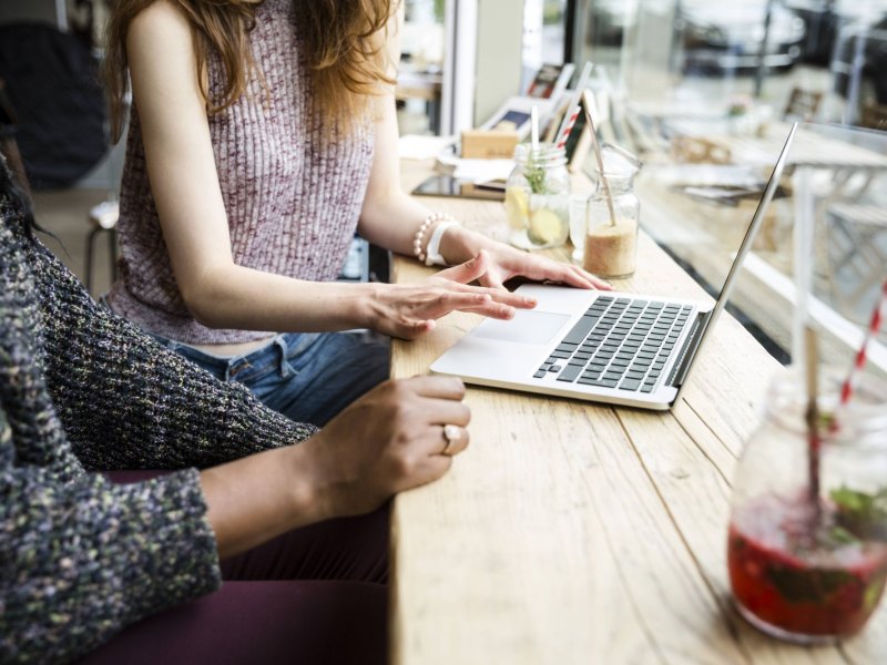 Zwei Frauen surfen im Café auf ihren Laptops im Internet.