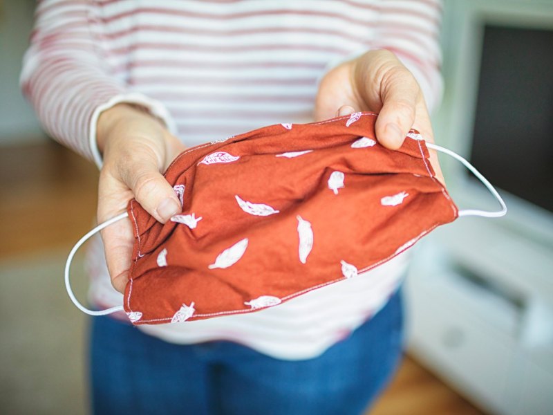 Frau hält DIY-Mundschutz in die Kamera