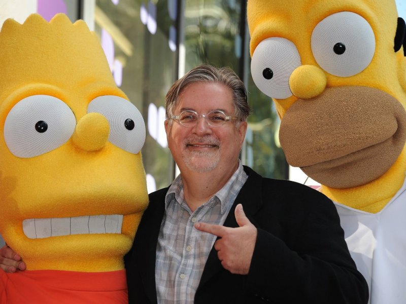 Zwei als Homer und Bart kostümierte Personen mit Simpsons-Erfinder Matt Groening in der MItte