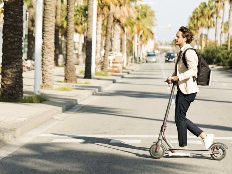 Mann fährst auf E-Scooter.