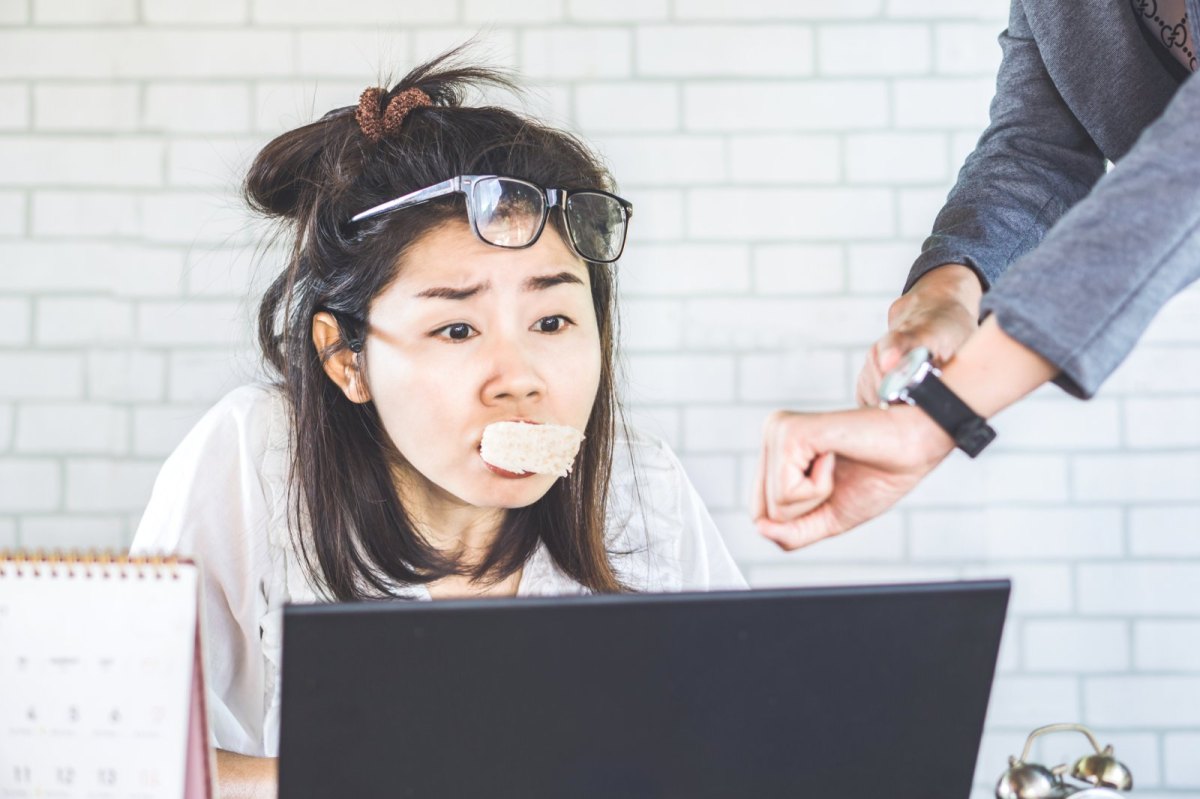 Frau mit Essen im Mund unter Zeitdruck