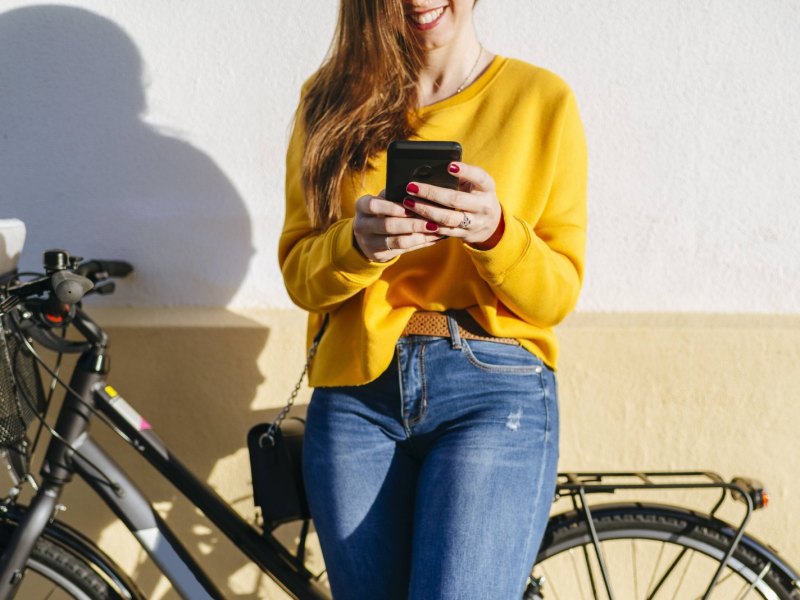 Frau mit Handy und Fahrrad.