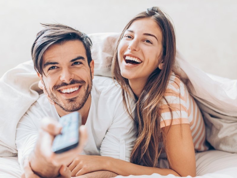 Mann und Frau im Bett mit Fernbedienung