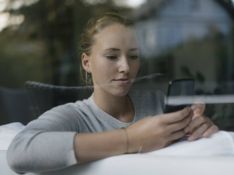 Junge Frau mit Handy auf dem Sofa