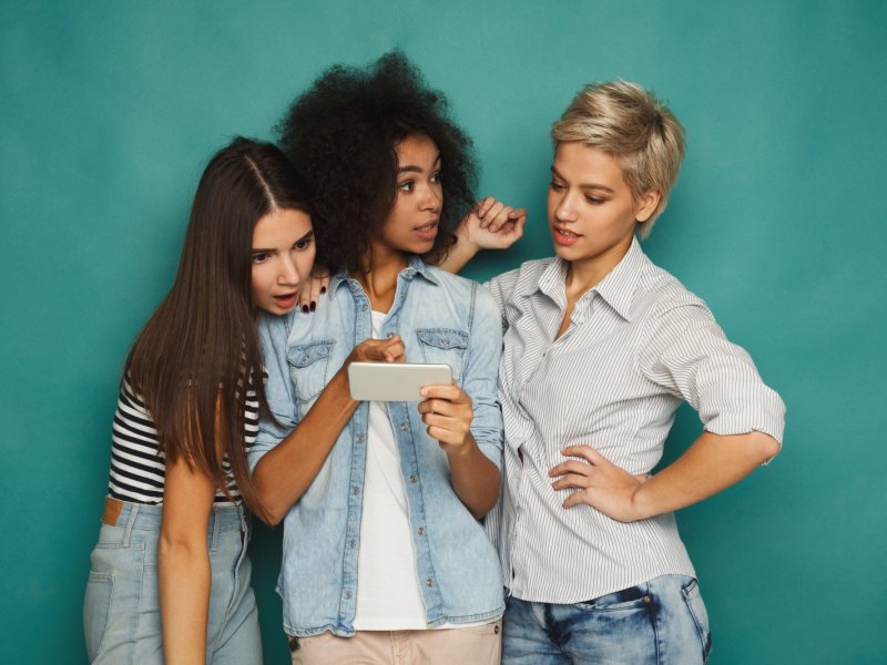 Drei Frauen gucken auf ein Smartphone.