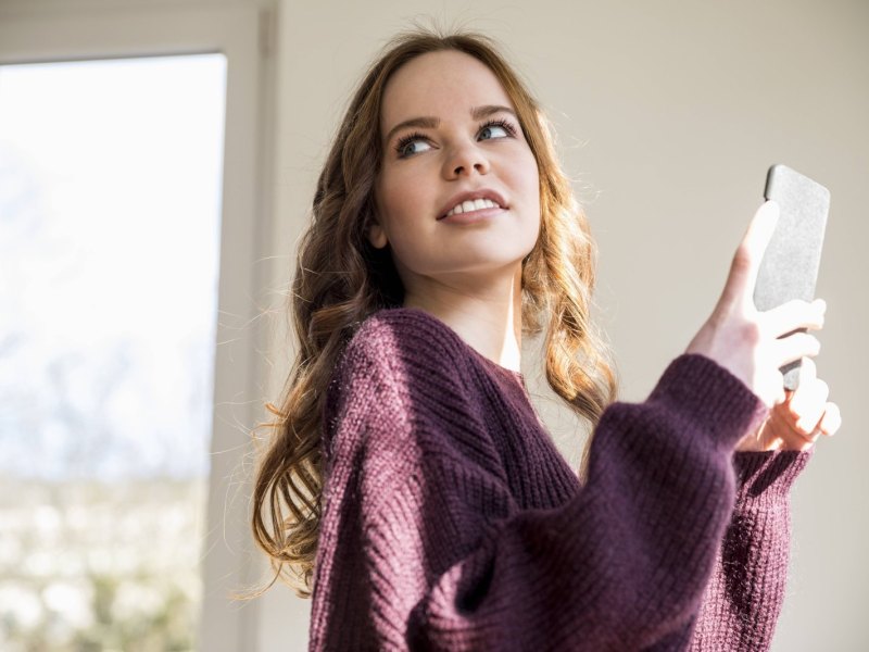 Frau hält ihr Handy in der Hand.