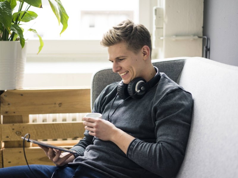 Mann mit Kopfhörern und Tablet.