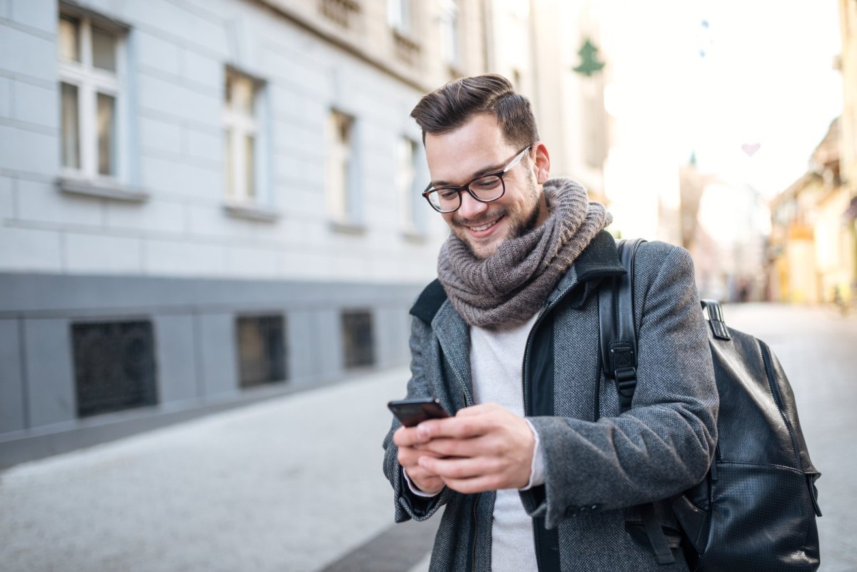 Mann guckt auf der Straße auf sein Handy.