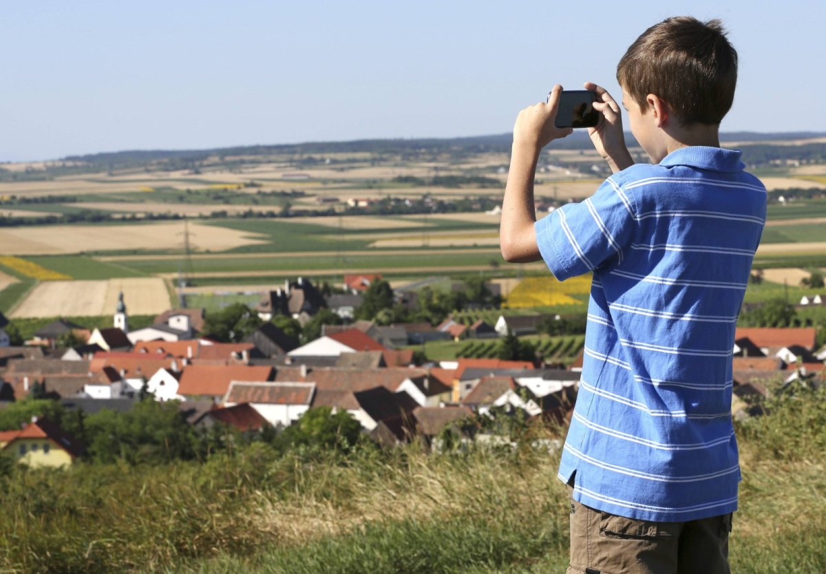 Junge mit Smartphone auf einem Hügel.