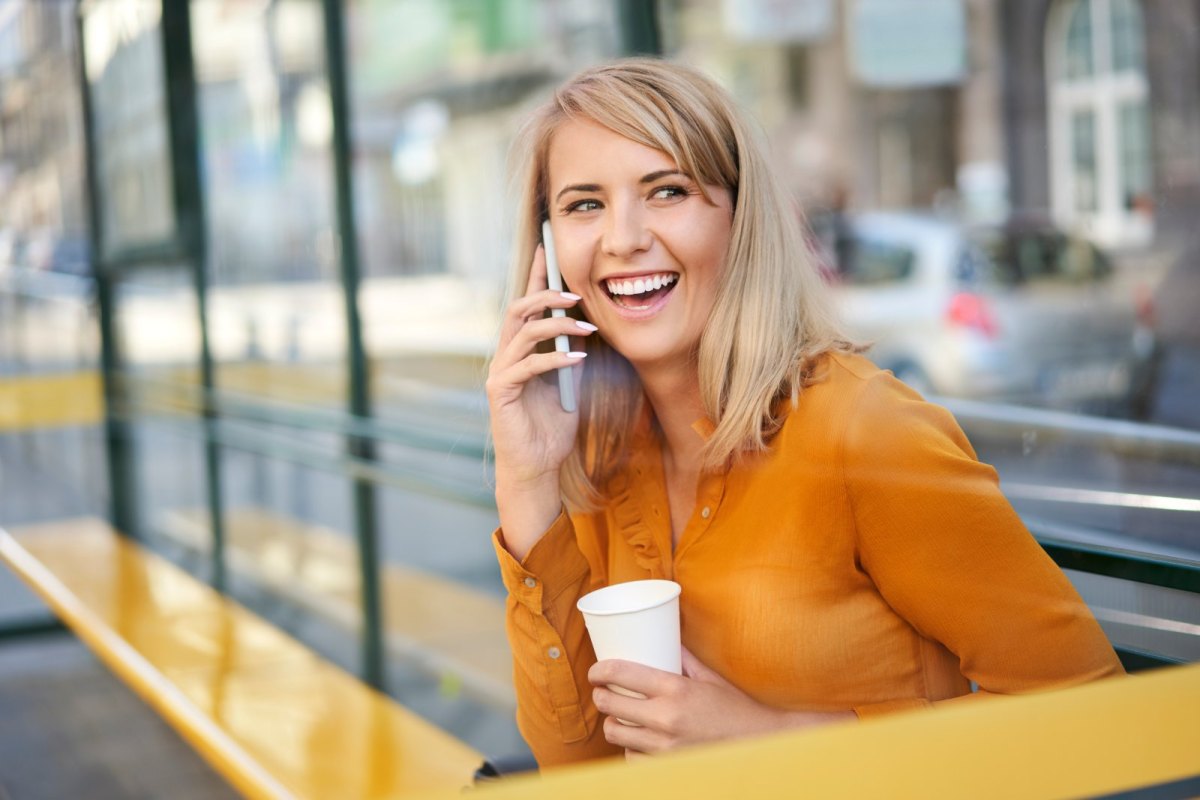 Frau telefoniert lachend mit ihrem Handy.