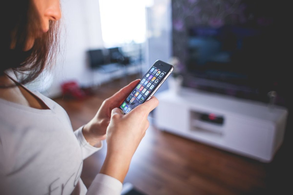 Eine Frau hält ihr iPhone in den Händen und guckt konzentriert.