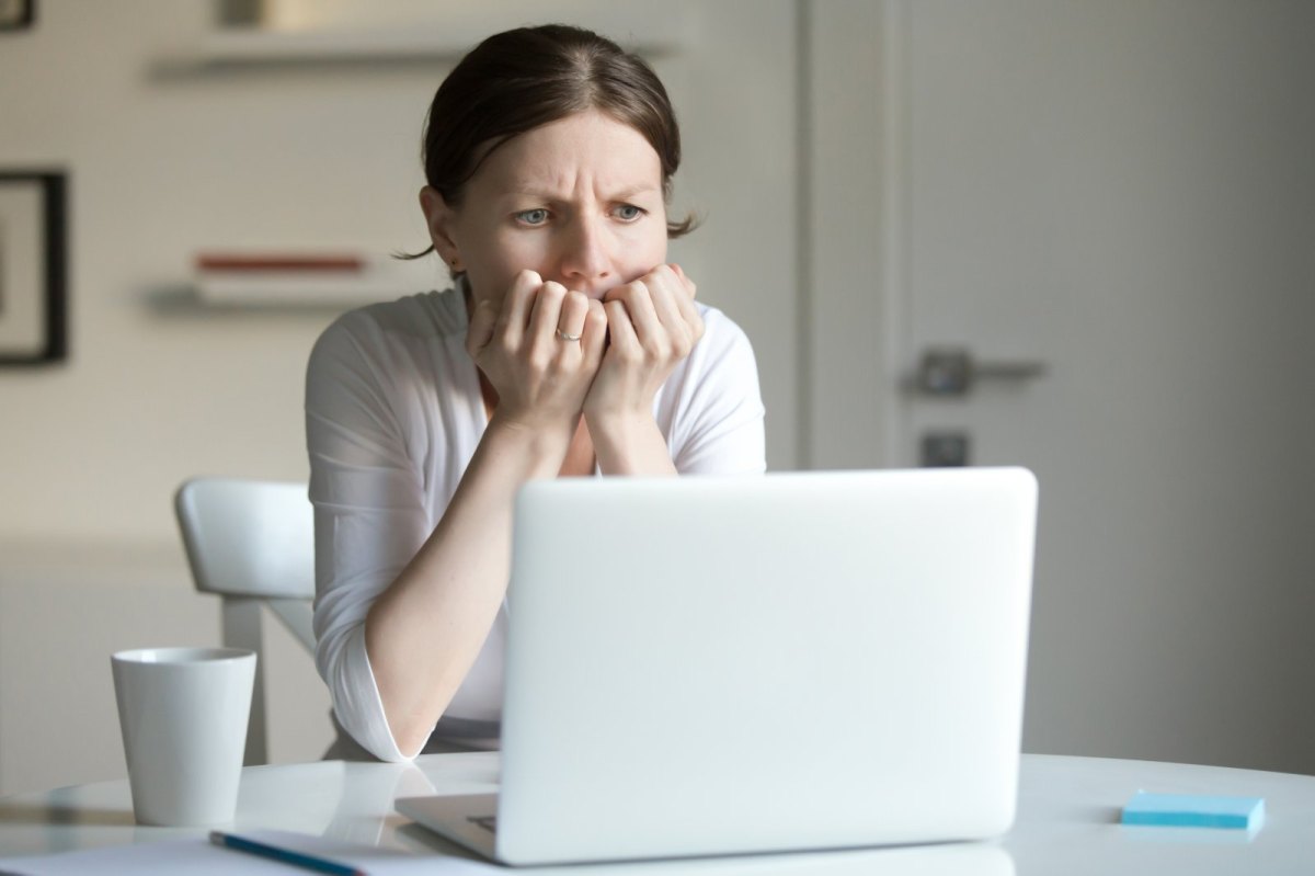 Frau sitzt besorgt vor dem Laptop.