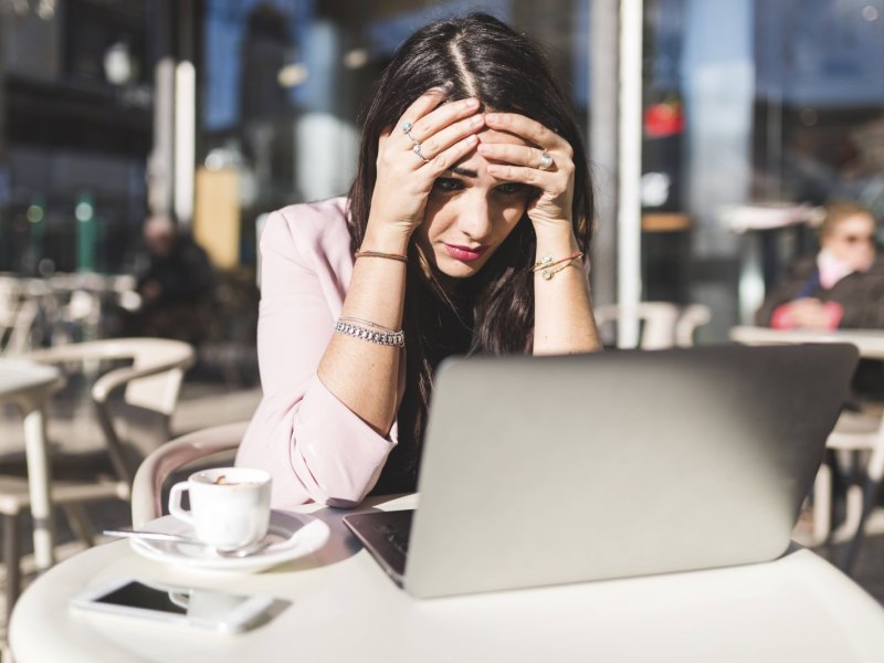 Eine Frau guckt auf ihren Laptop und ist verzweifelt