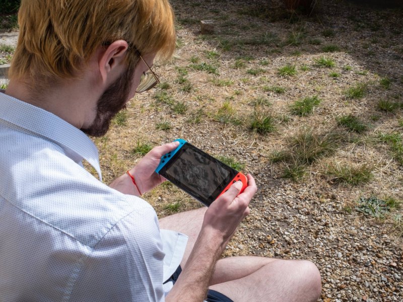 Mann spielt Nintendo Switch im Garten