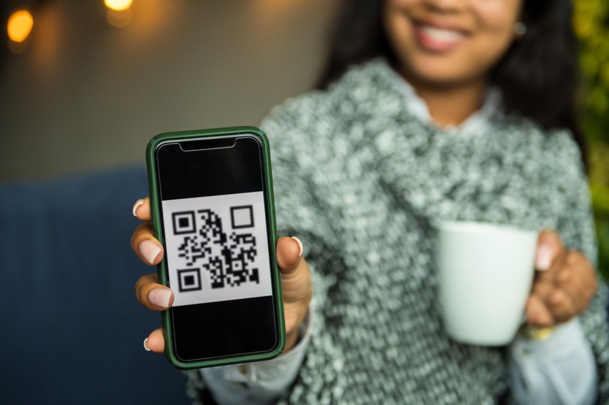 Frau hält Handy mit QR-Code auf dem Display in die Kamera.