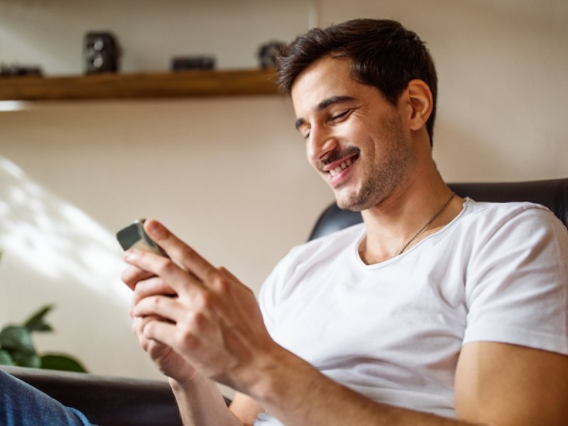 Mann mit kleinem Smartphone in der Hand.