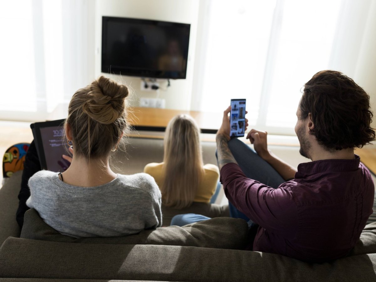 Familie sitzt gemeinsam vorm Fernseher.