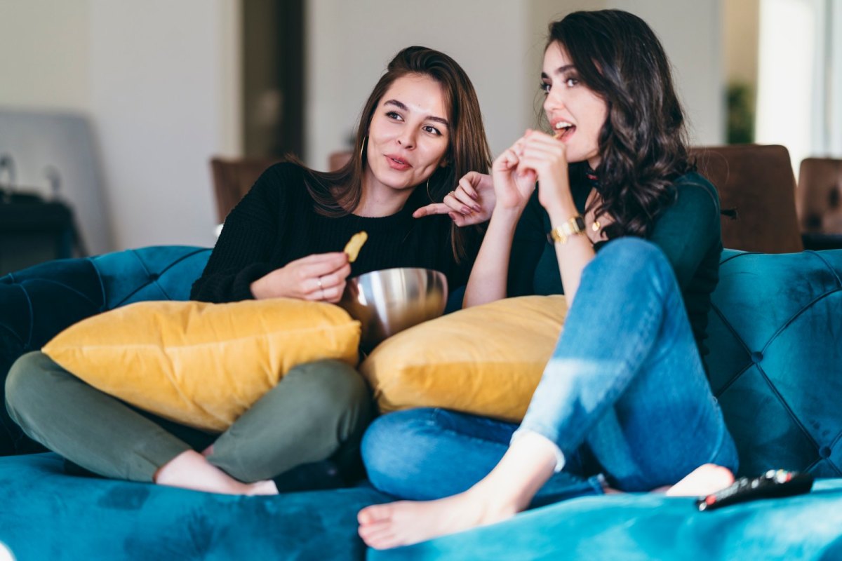 Zwei Frauen auf dem Sofa mit Snacks.