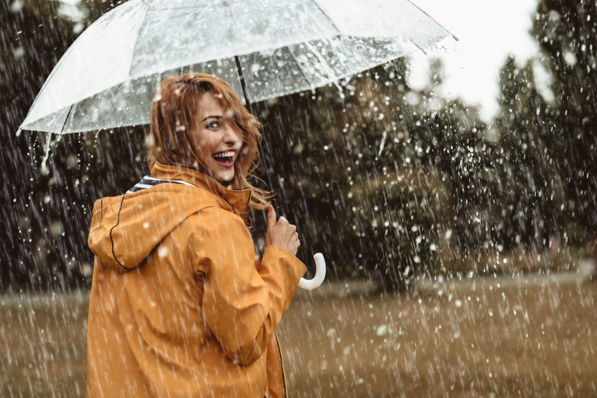 Frau mit Regenschirm geht im Regen spazieren