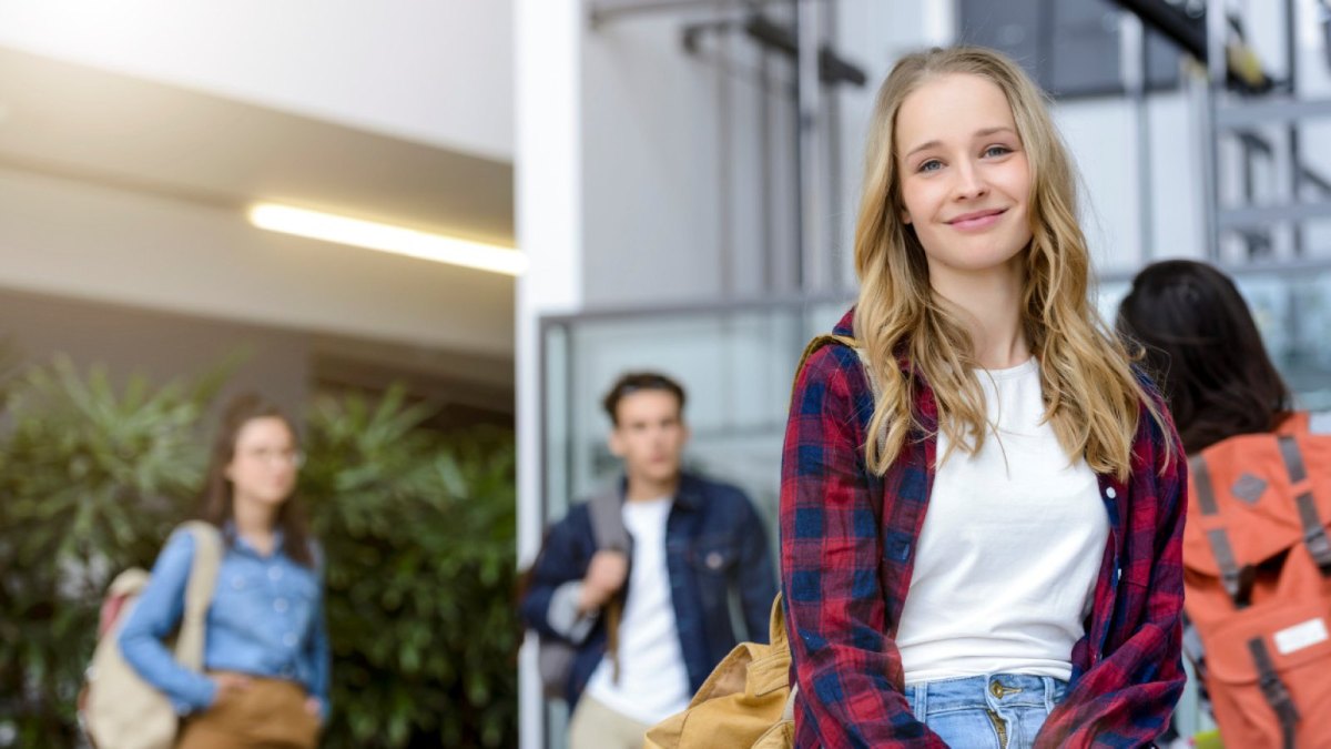 Junge Studentin lächelt und blickt zuversichtlich in die Zukunft.