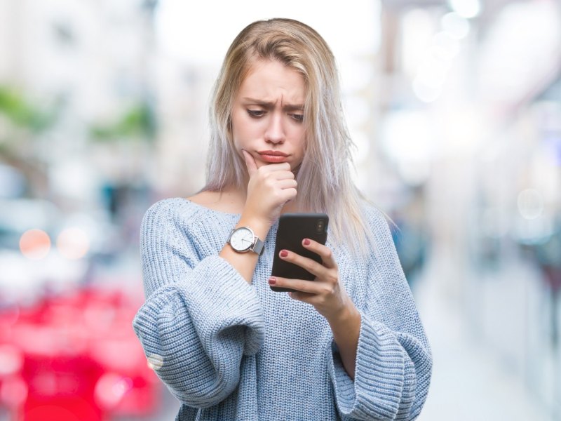 Frau schaut skeptisch auf ihr Handy