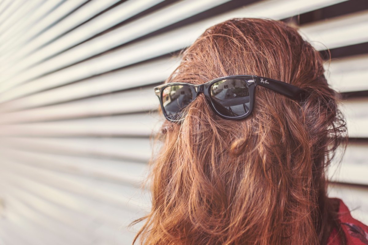 Frau mit Haaren im Gesicht und Sonnenbrille