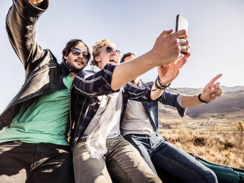 Drei Freunde sind unterwegs und filmen sich mit dem Handy.