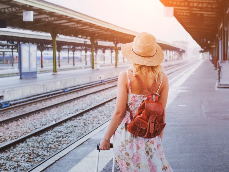 Frau am Bahnhof mit Koffer