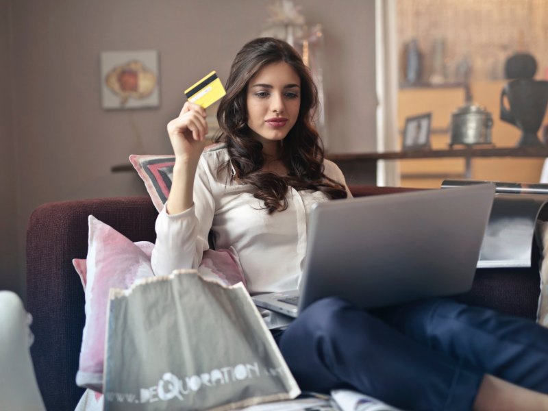 Frau sitzt mit ihrem Laptop auf dem Sofa