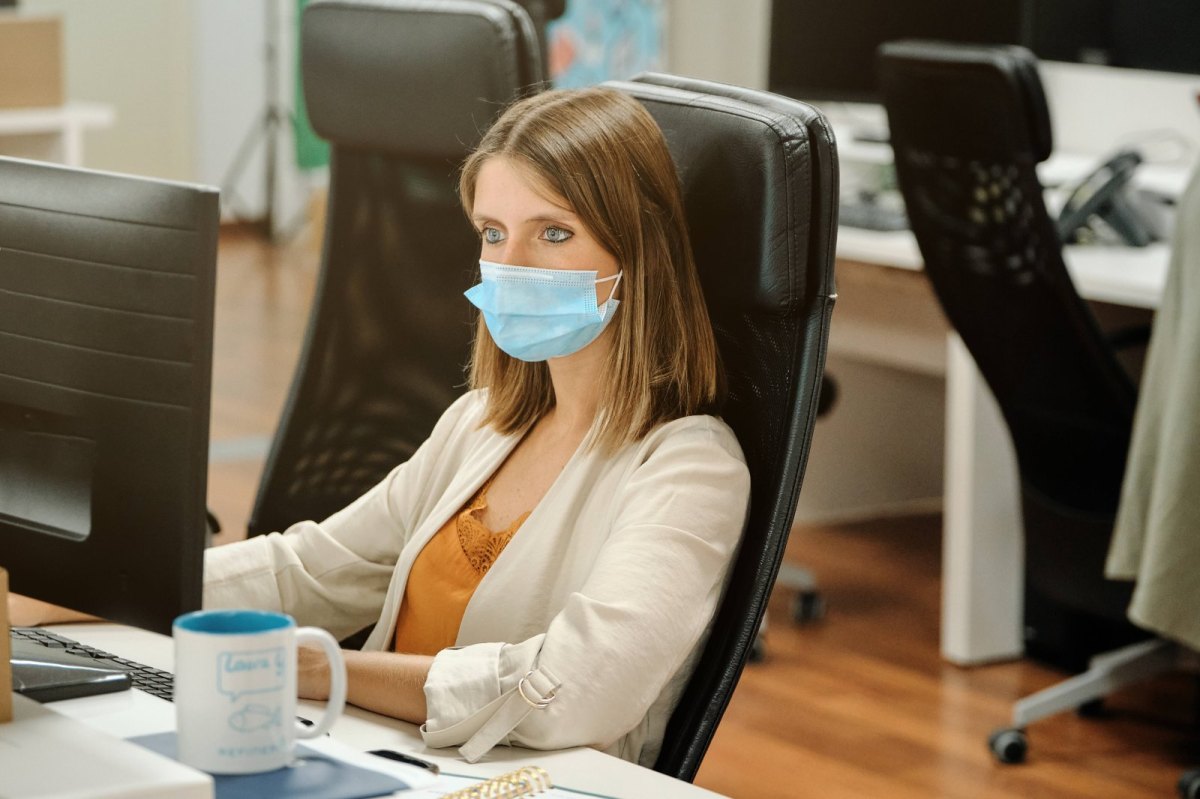 Frau am Arbeitsplatz mit Corona maske