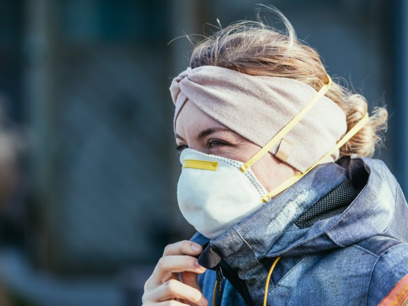 Frau mit Maske in Winterjacke