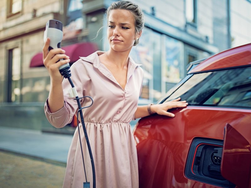 Frau beim Aufladen eines Elektroautos