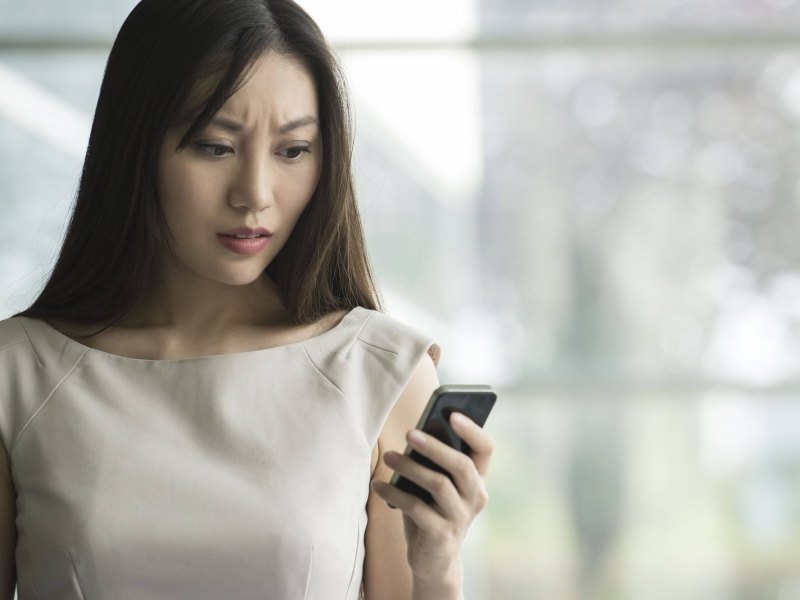 Frau schaut enttäuscht aufs Handy