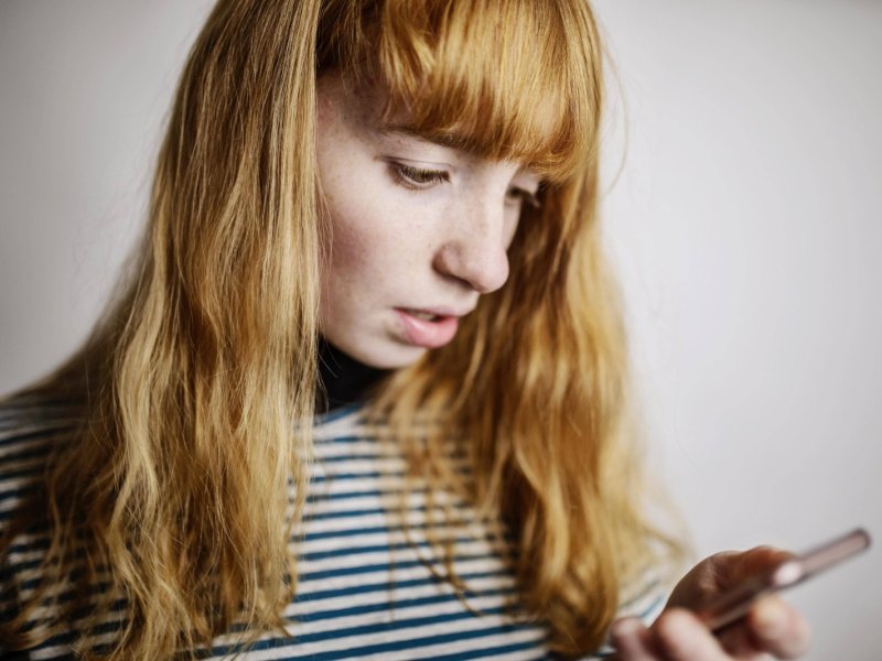 Frau schaut enttäuscht aufs Handy