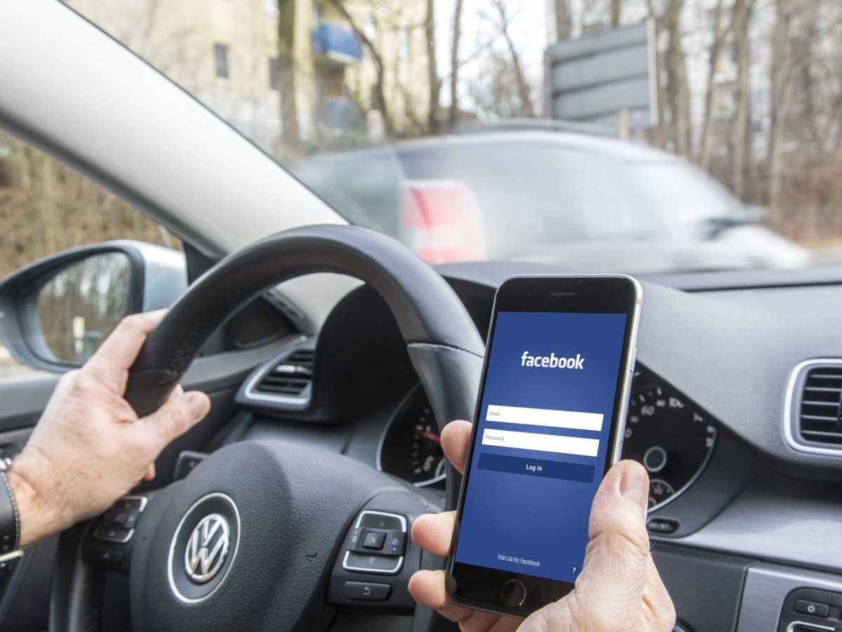 Mann im Auto mit Facebook auf dem handy