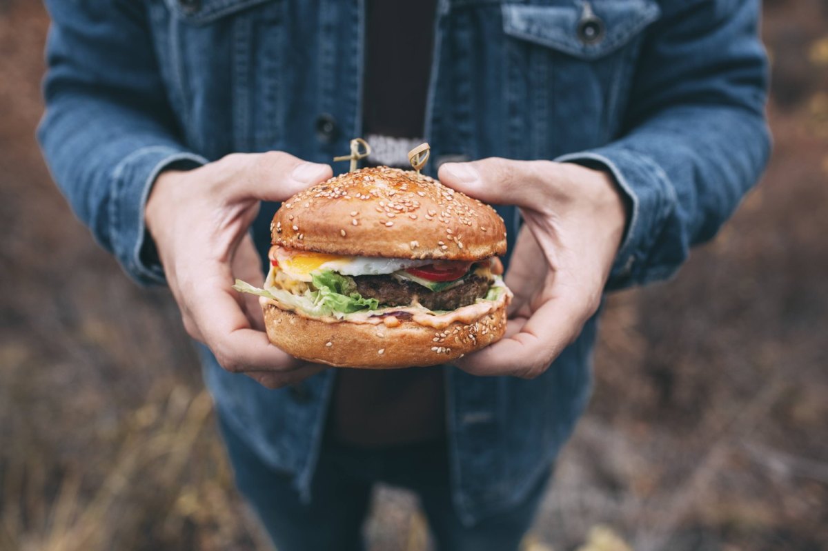 Mann hält Burger in die Kamera