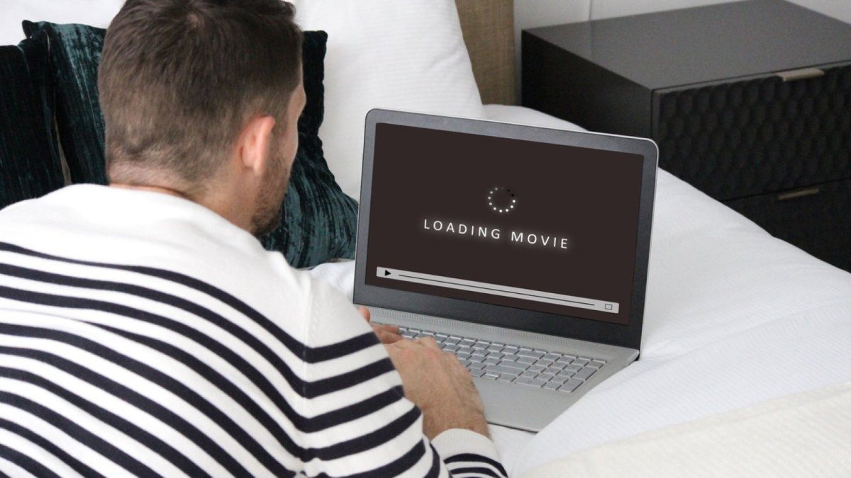 Mann lädt einen Film auf seinen Laptop.