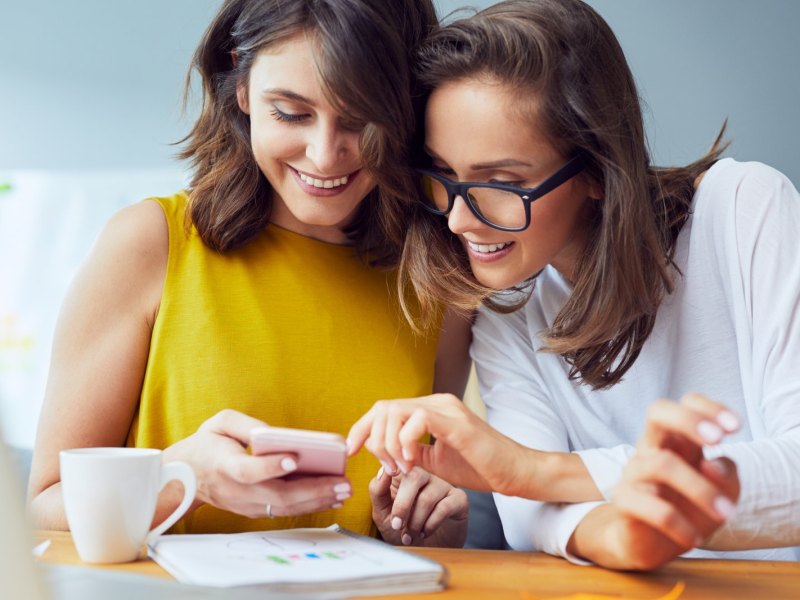 Zwei Frauen schauen auf ein Handy.