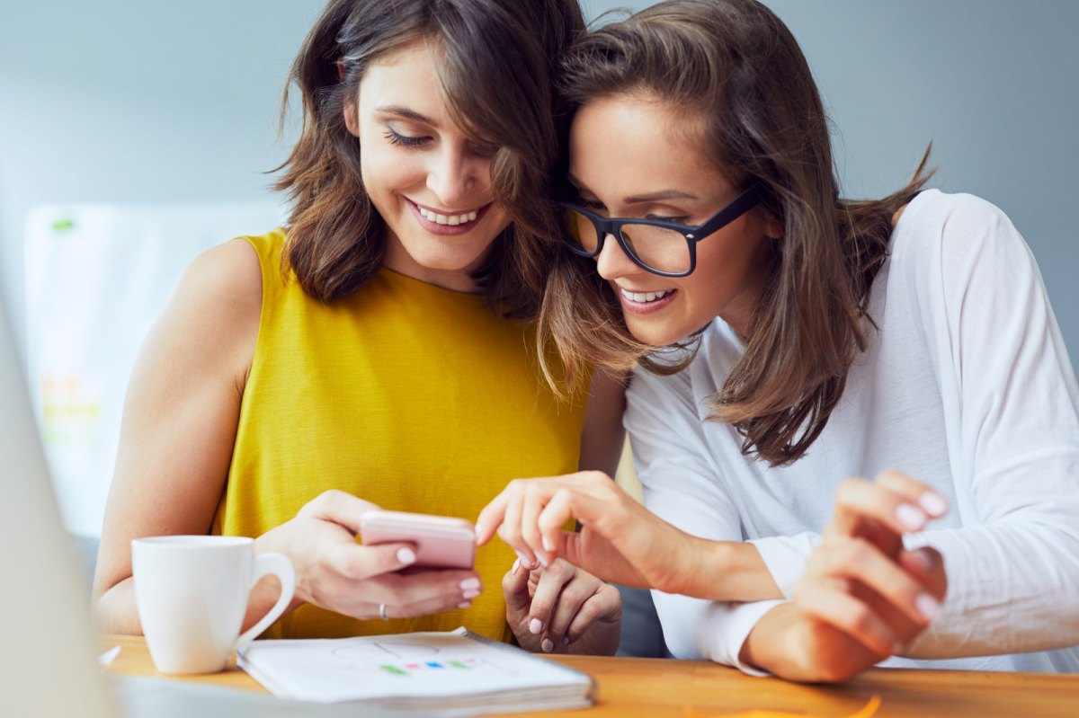 Zwei Frauen schauen auf ein Handy.