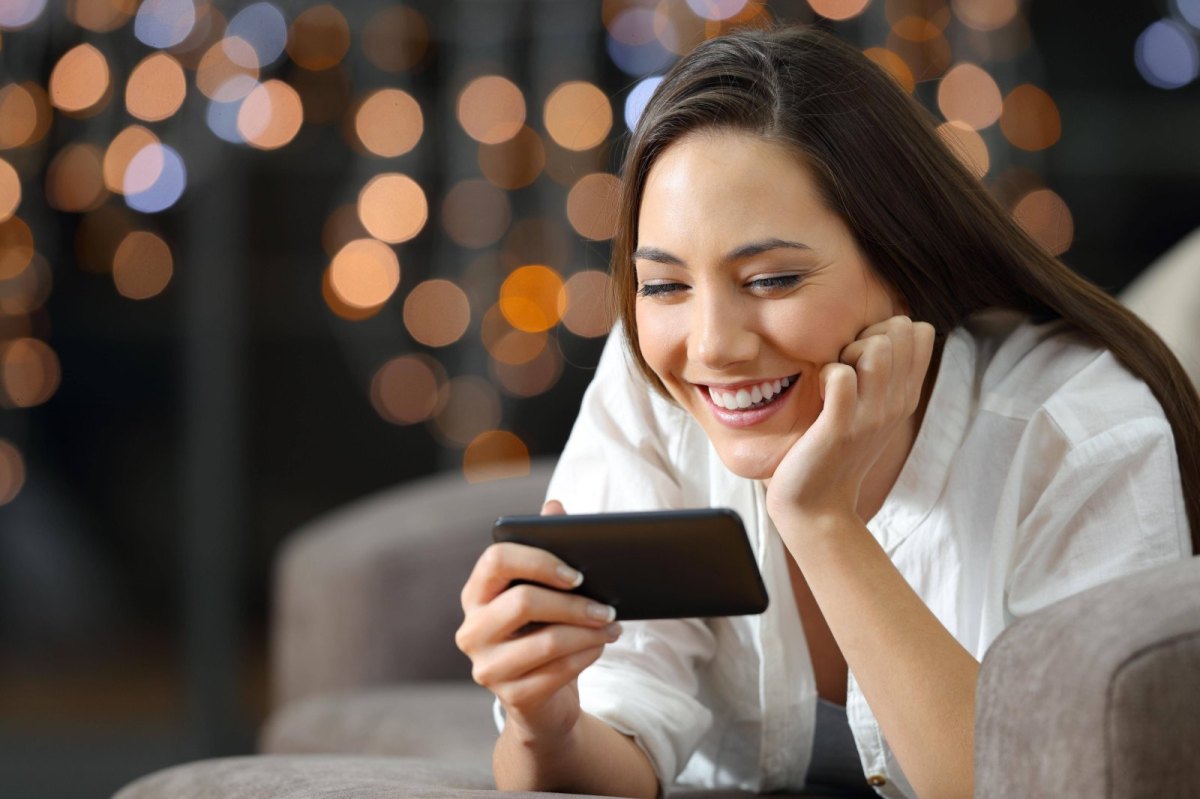 Frau guckt auf ihr Handy und freut sich