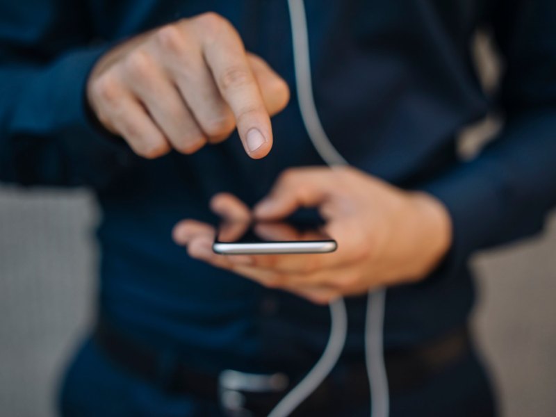 Mann zeigt mit Finger auf handydisplay