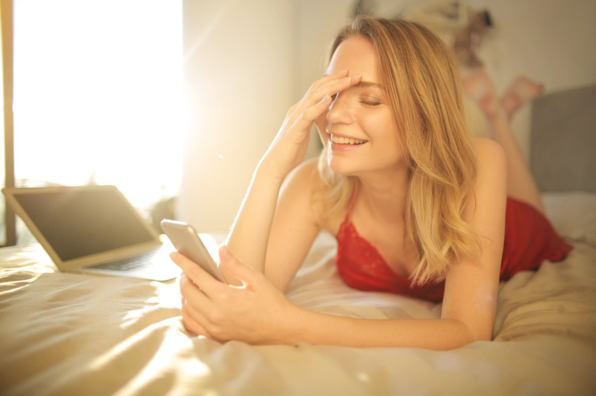 Peinlich berührt blickt eine junge Frau auf ihre Handy.