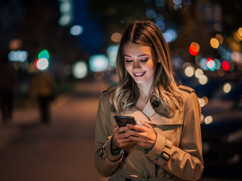 Frau schaut lächelnd auf ihr Handy.