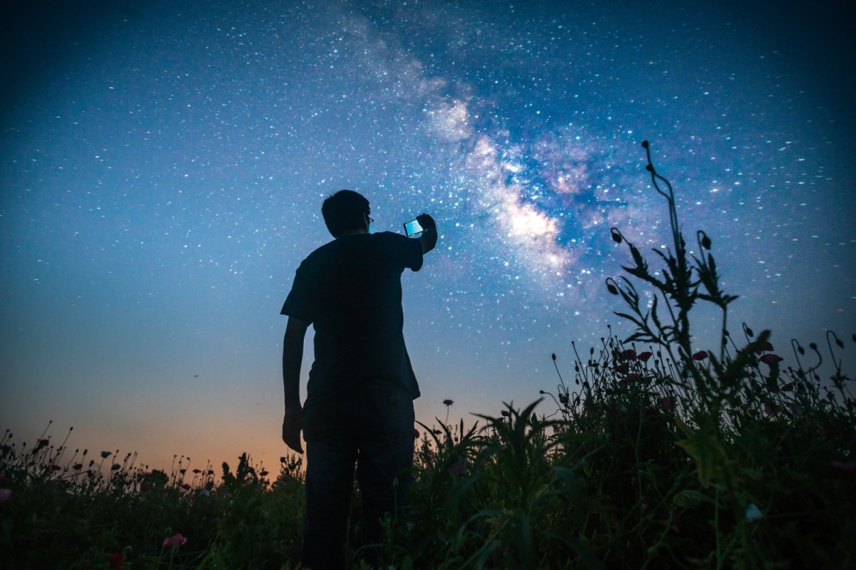 Mann mit Handy fotografiert den Sternenhimmel