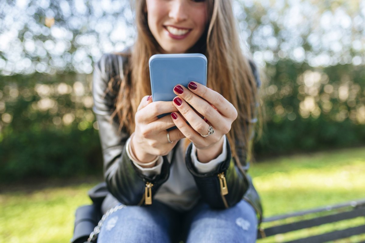 Junge Frau hält iPhone in der Hand.